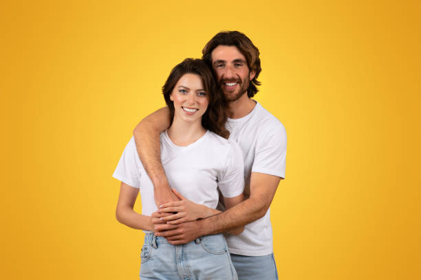 istock Affectionate and joyful couple in matching white t-shirts embracing lovingly 2153049333