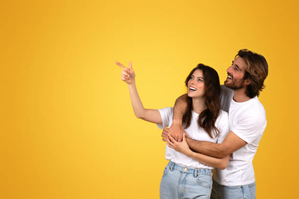 istock Smiling woman in a white shirt pointing upwards while being embraced 2153049587
