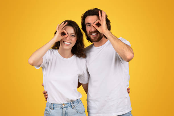 istock Playful couple making fun gestures with their hands over one eye, smiling and sharing a joyful 2153049624