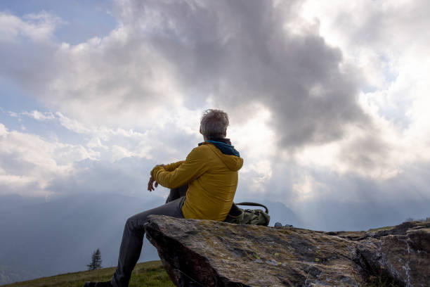 istock Mature hiker watches sunrise through clouds 2153050525
