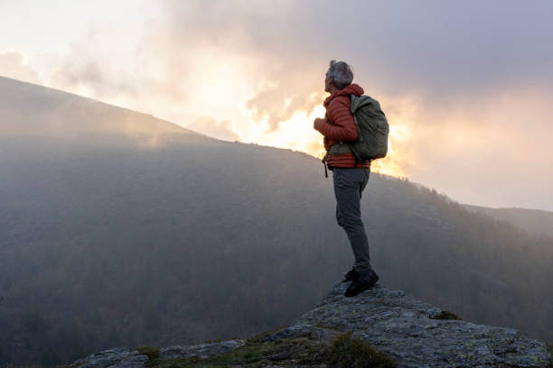 istock Mature hiker pauses on rock above misty hills 2153050950