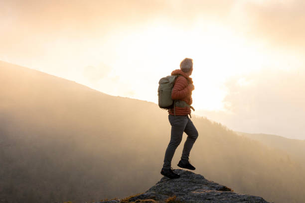 istock Mature hiker pauses on rock above misty hills 2153051003
