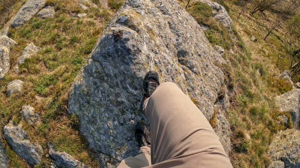 POV of hiker's feet stepping onto rock above valley