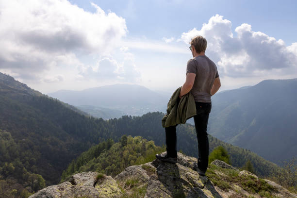 istock Young man pauses on hill above valley and mountains 2153051477