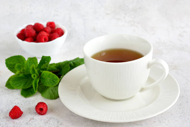 a cup of mint tea and a plate of raspberry close up