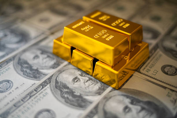 Gold and Money: This image features shiny gold bars on a stack of $100 bills, perfect for content related to investments, economics, and the financial market.