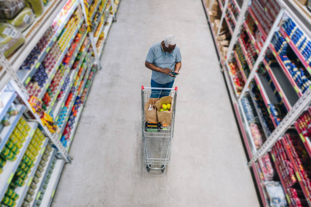 Senior man using the mobile phone at the supermarket