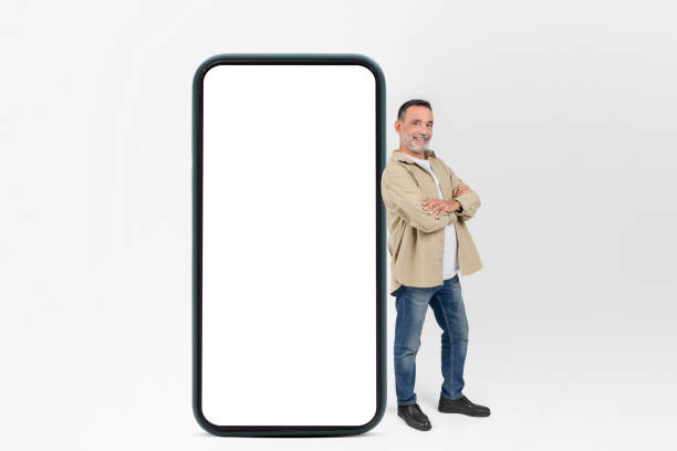 istock Smiling man standing with giant smartphone, mockup 2153052322