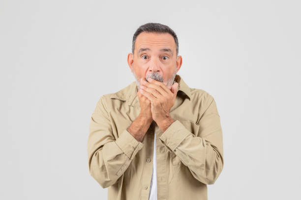 istock Elderly man covering mouth in surprise on white 2153052511