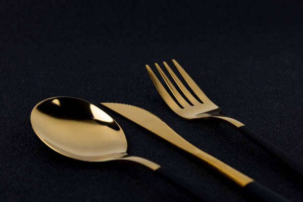 istock Gold plated cutlery on black concrete background close up 2153057882