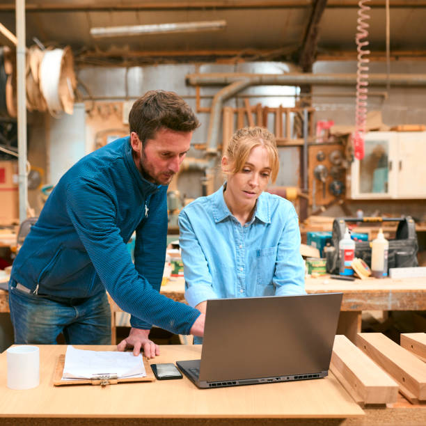istock Male And Female Carpenters Working In Woodwork Workshop Using Laptop Together 2153060900