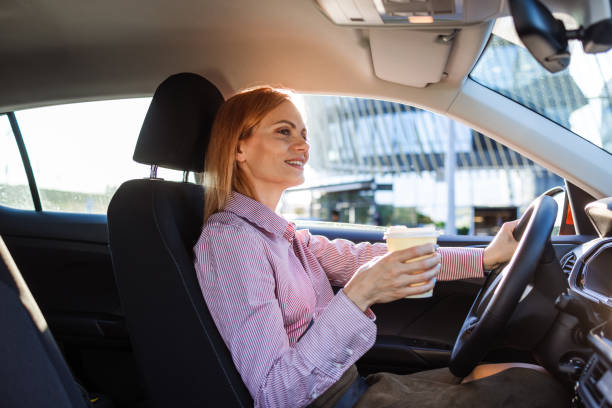 istock Woman driving car and holding coffee cup 2153064129
