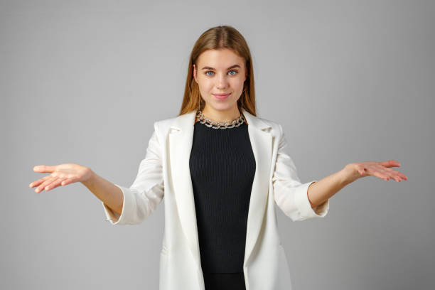 istock Young Woman Expressing Confusion With Hands Raised Against a Grey Background 2153065081