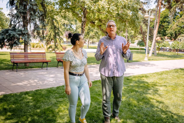 istock 50 year old man spending quality time with his 20 year old daughter outdoors walking and talking in public park 2153074706