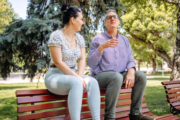 istock 50 year old man spending quality time with his university student daughter outdoors in public park and talking 2153074708
