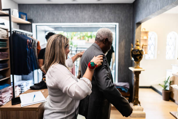 istock Tailor helping a senior man putting on a suit at clothing store 2153081317