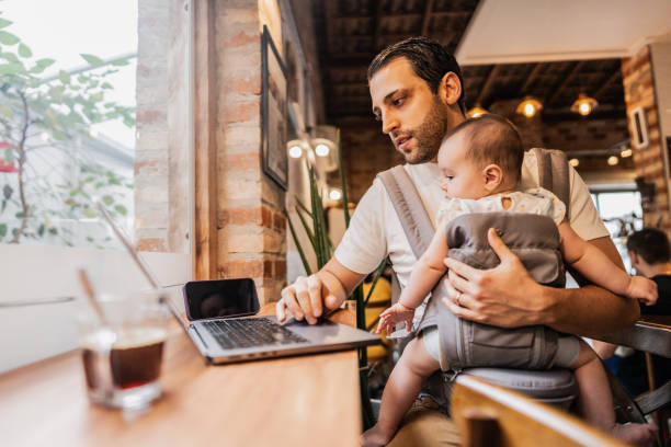 istock Father working using laptop with his daughter on lap at coffee shop 2153082771