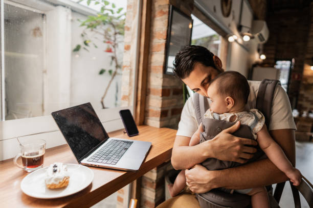 istock Father working using laptop with his daughter on lap at coffee shop 2153082774
