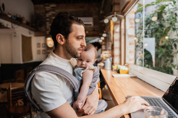 istock Father working using laptop with his daughter on lap at coffee shop 2153082799