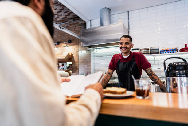 istock Young waiter talking with customer at coffee shop 2153083722