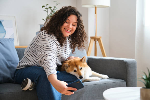 istock A woman is sitting on a couch taking a selfie with her dog. 2153085916