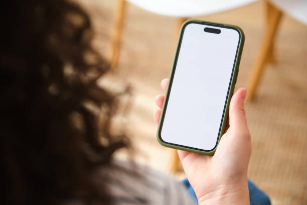 A person is holding a cell phone with a blank screen mock up.