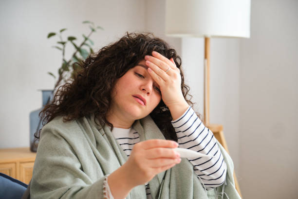 istock A woman with a fever is holding a thermometer 2153086851