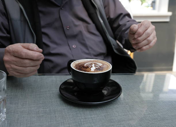 A Canadian senior man with a cup of mocha coffee during lunch at a cafe. Spring afternoon in Metro Vancouver.