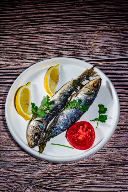 A plate of fish and lemon slices on a wooden table