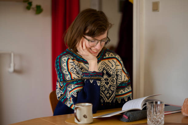 istock Young woman sitting at her kitchen table with a book 2153089902