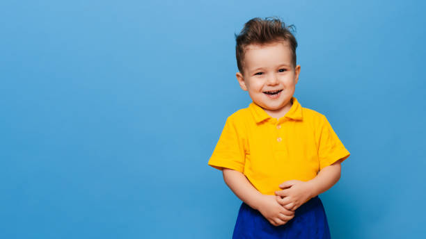 istock Cute little grimaces stands on a blue background. Funny kid 2153090161