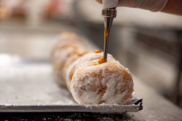 istock Baker filling donuts with a caramel sauce at an industrial bakery 2153090618
