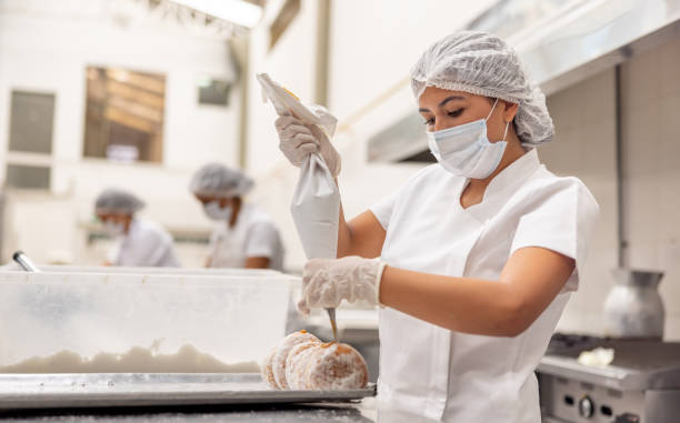 istock Baker filling donuts with a caramel sauce at an industrial bakery 2153090640