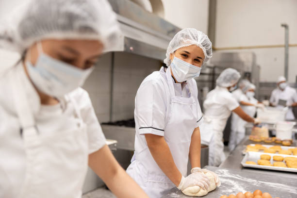 istock Happy baker working at a food processing plant kneading the dough 2153090645