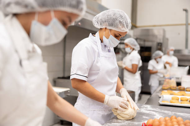 istock Baker working at an industrial bakery kneading the dough 2153090677