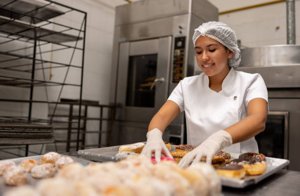 istock Woman working at an industrial bakery making donuts 2153090680