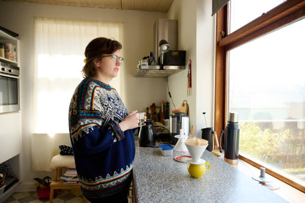 istock Young woman in kitchen looking out of window 2153091839