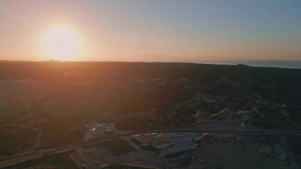 istock Sunset casting orange glow over landscape aerial view. Roadway distant buildings 2153092444