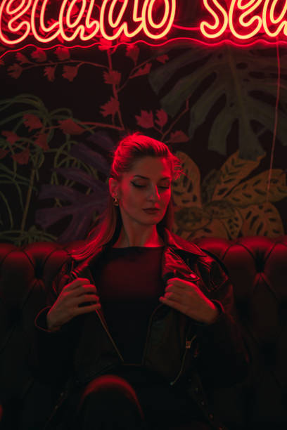 istock Young woman in a dark lounge under red neon light at night 2153092641