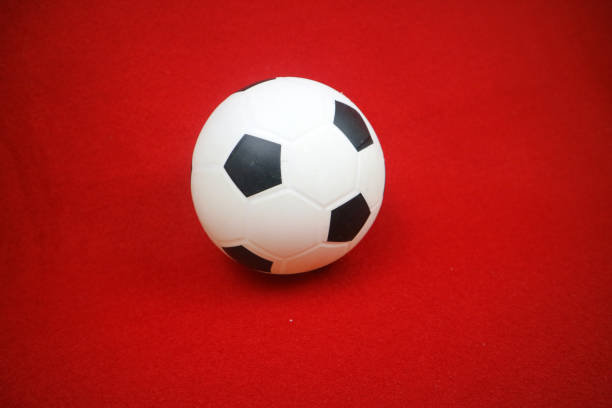 istock a small white and black toy rubber ball. Red background 2153093096