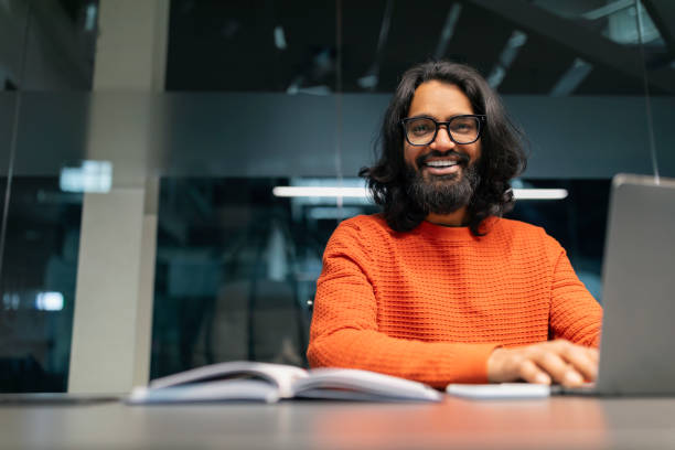 istock Smiling young indian businessman sitting at worktable at modern office 2153093976