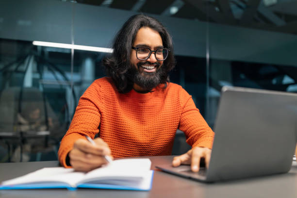 istock Cheerful bearded hindu man engages with his laptop, taking notes 2153094253