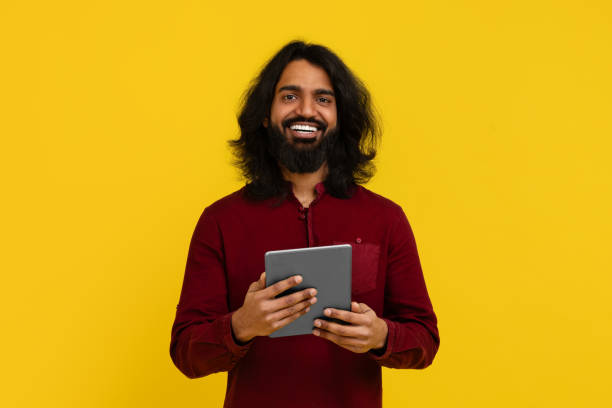 istock Positive young indian man holding digital tablet, yellow background 2153096726