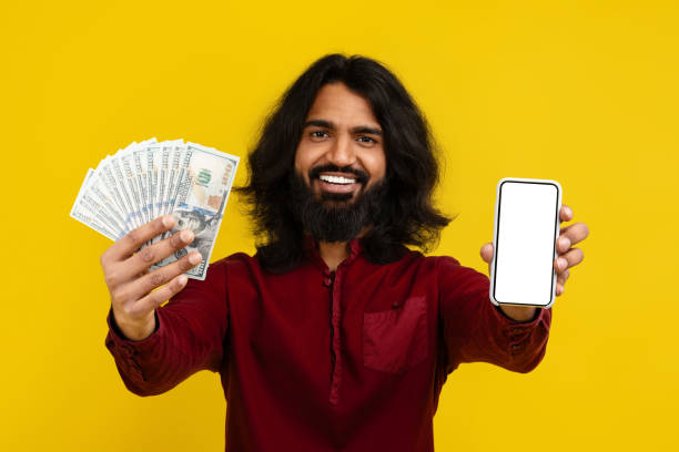 istock Happy eastern man showing cash and phone with blank screen 2153096844