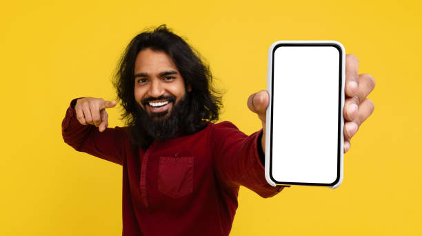 istock Cheerful young indian man pointing at phone in his hand 2153096885