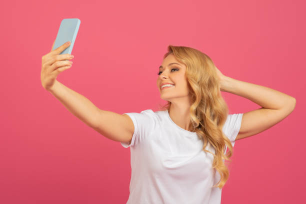 istock Young attractive blonde taking a selfie with her smartphone, studio 2153098369