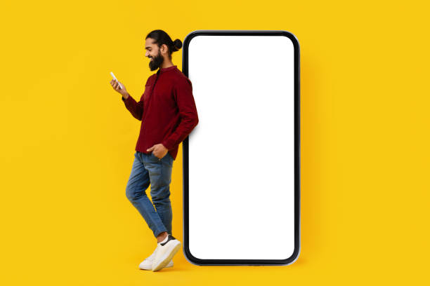 istock Man in Casual Attire Leaning on Large Blank Smartphone Screen 2153098513