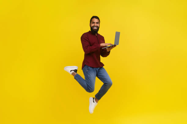 istock Excited eastern man with laptop jumping on yellow background 2153098528