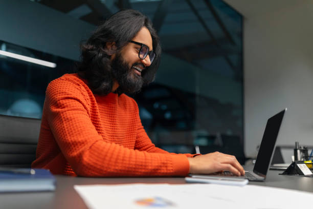 istock Joyful man typing on a laptop in the office 2153100122
