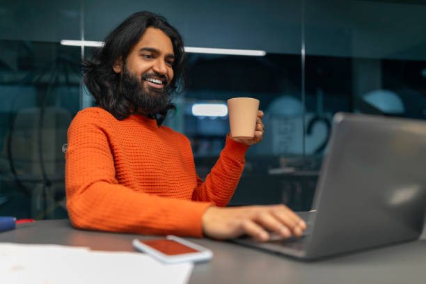 istock Happy man with cup engaging with laptop 2153100140